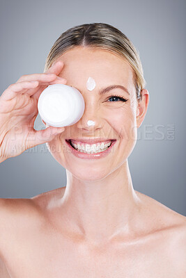 Buy stock photo Studio portrait of an attractive mature woman applying moisturiser on her face against a grey background