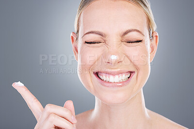 Buy stock photo Studio shot of an attractive mature woman applying moisturiser on her face against a grey background