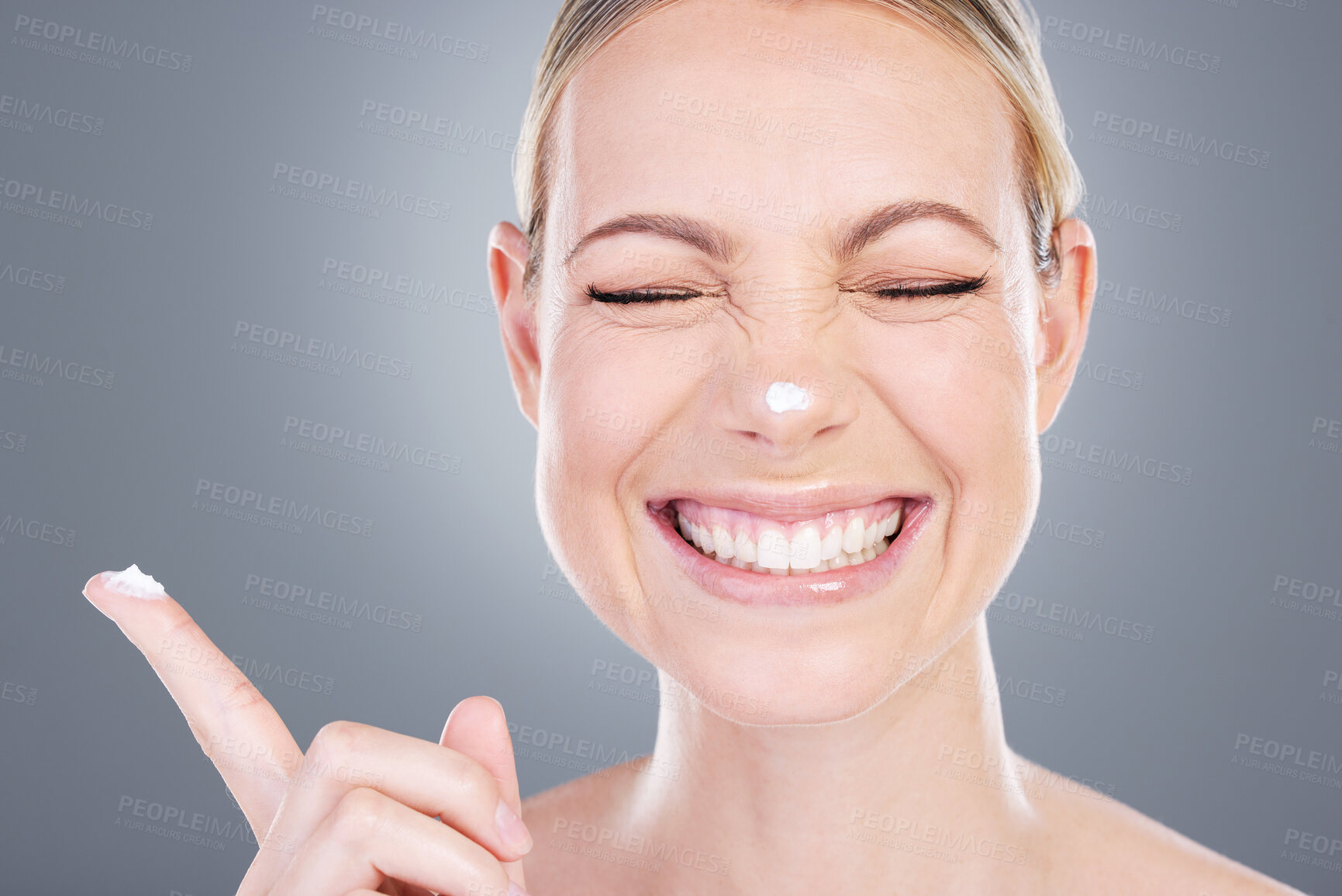 Buy stock photo Happy woman, skincare and nose with lotion for moisturizer or facial treatment on a gray studio background. Fun female person or model with smile in satisfaction or joy for anti aging or face cream