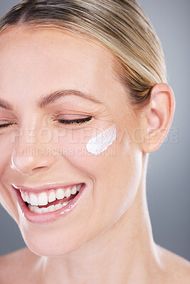 Buy stock photo Studio shot of an attractive mature woman applying moisturiser on her face against a grey background