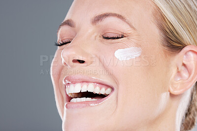 Buy stock photo Studio shot of an attractive mature woman applying moisturiser on her face against a grey background