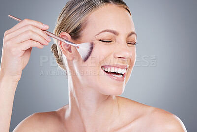Buy stock photo Studio shot of an attractive mature woman applying makeup to her face with a brush against a grey background