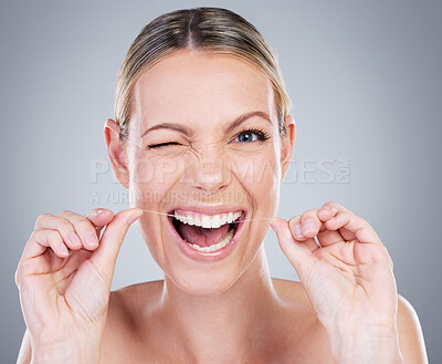 Buy stock photo Happy woman, portrait and floss teeth in studio, orthodontics and cosmetics on gray background. Female person, dental health and string for grooming, wink cleaning and self care or thread for plaque