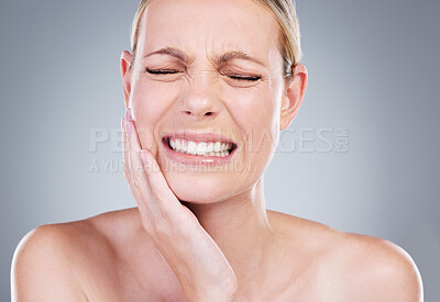 Buy stock photo Studio shot of an attractive mature woman experiencing toothache against a grey background