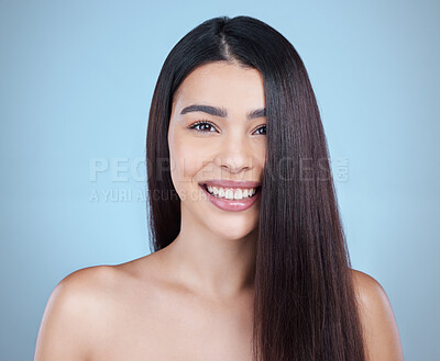 Buy stock photo Studio portrait of a beautiful young woman showing off her long silky hair against a blue background