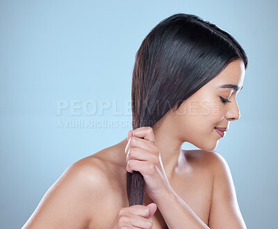 Buy stock photo Studio shot of a beautiful young woman showing off her long silky hair against a blue background