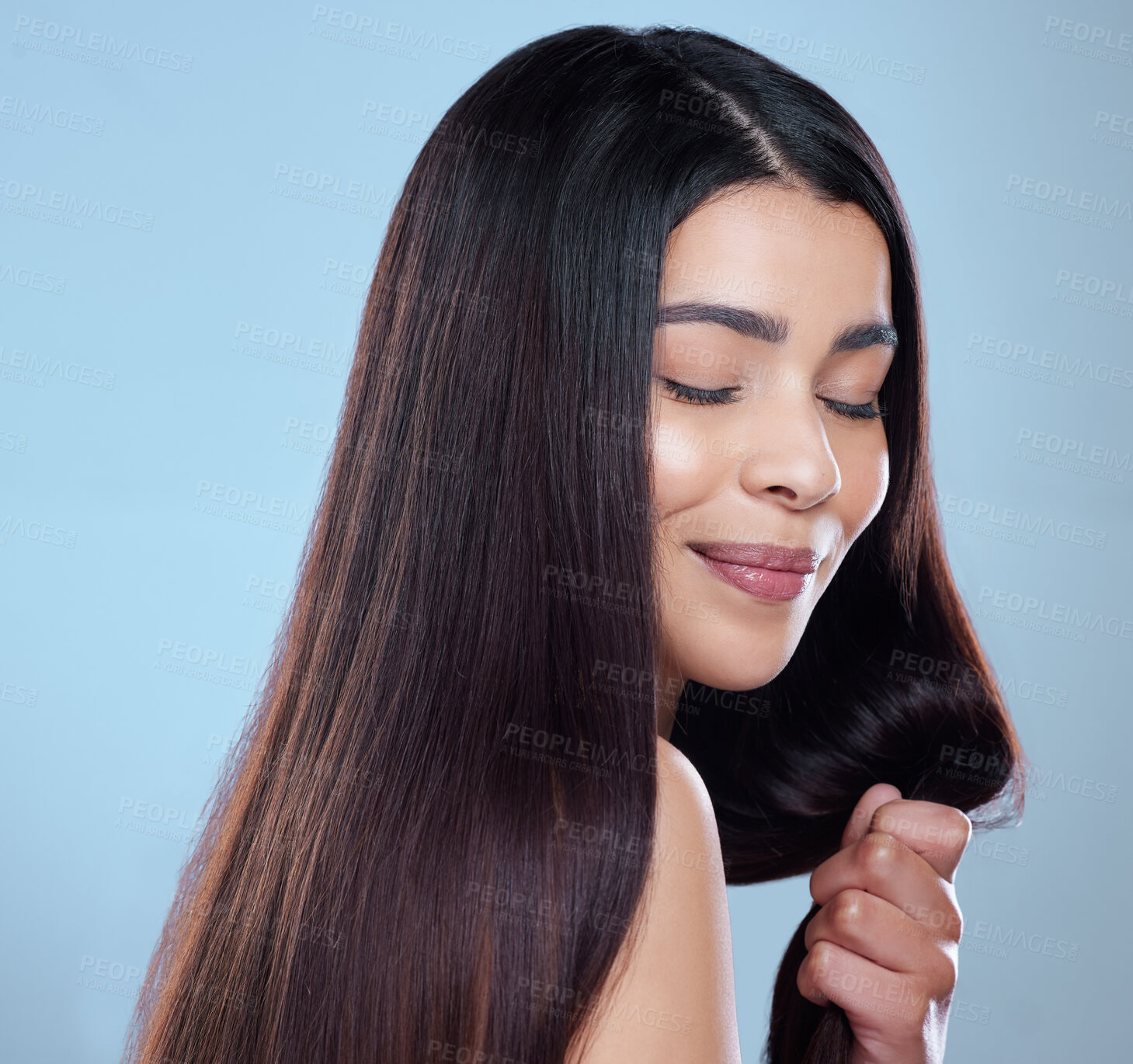 Buy stock photo Studio shot of a beautiful young woman showing off her long silky hair against a blue background