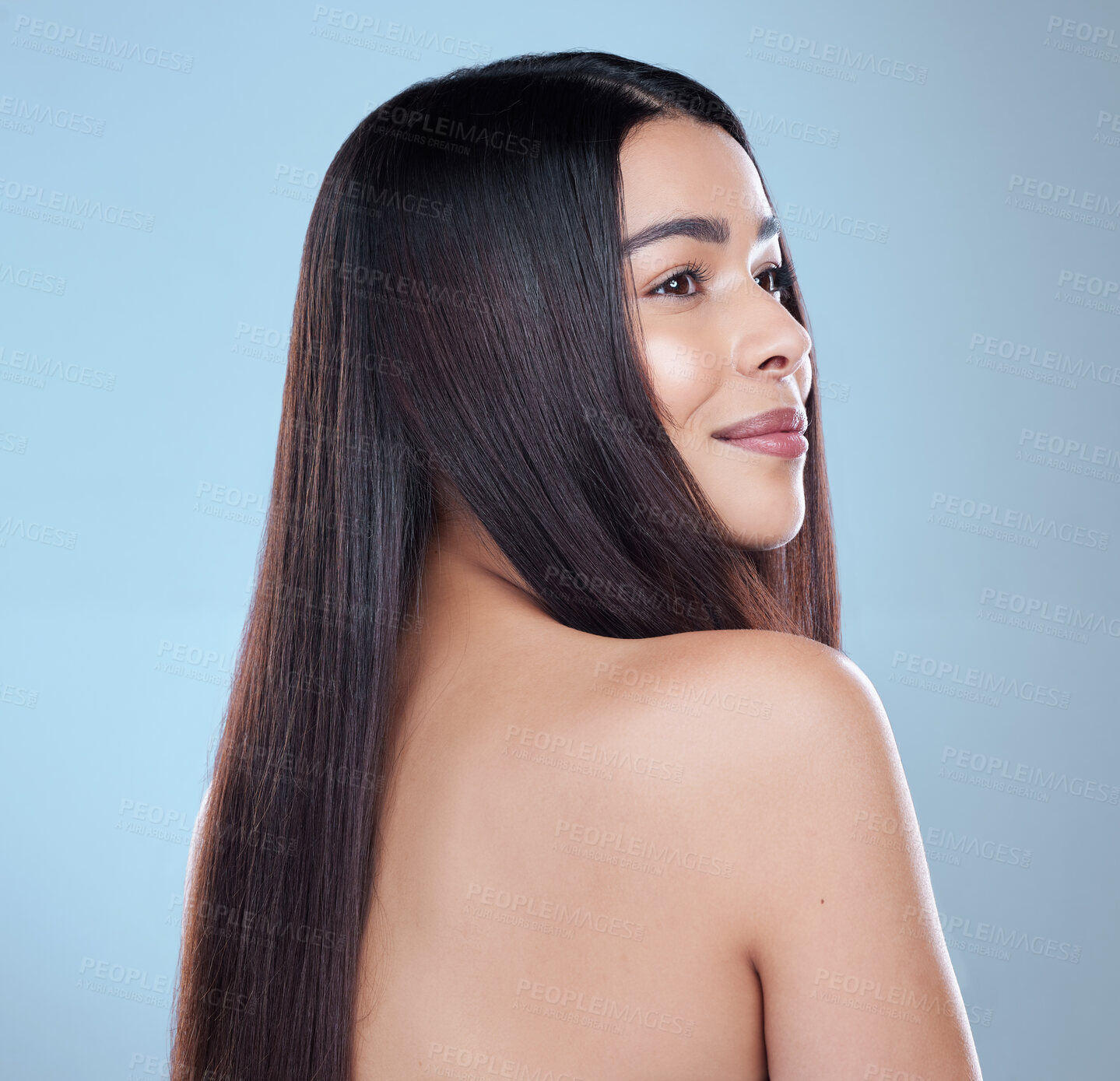 Buy stock photo Studio shot of a beautiful young woman showing off her long silky hair against a blue background