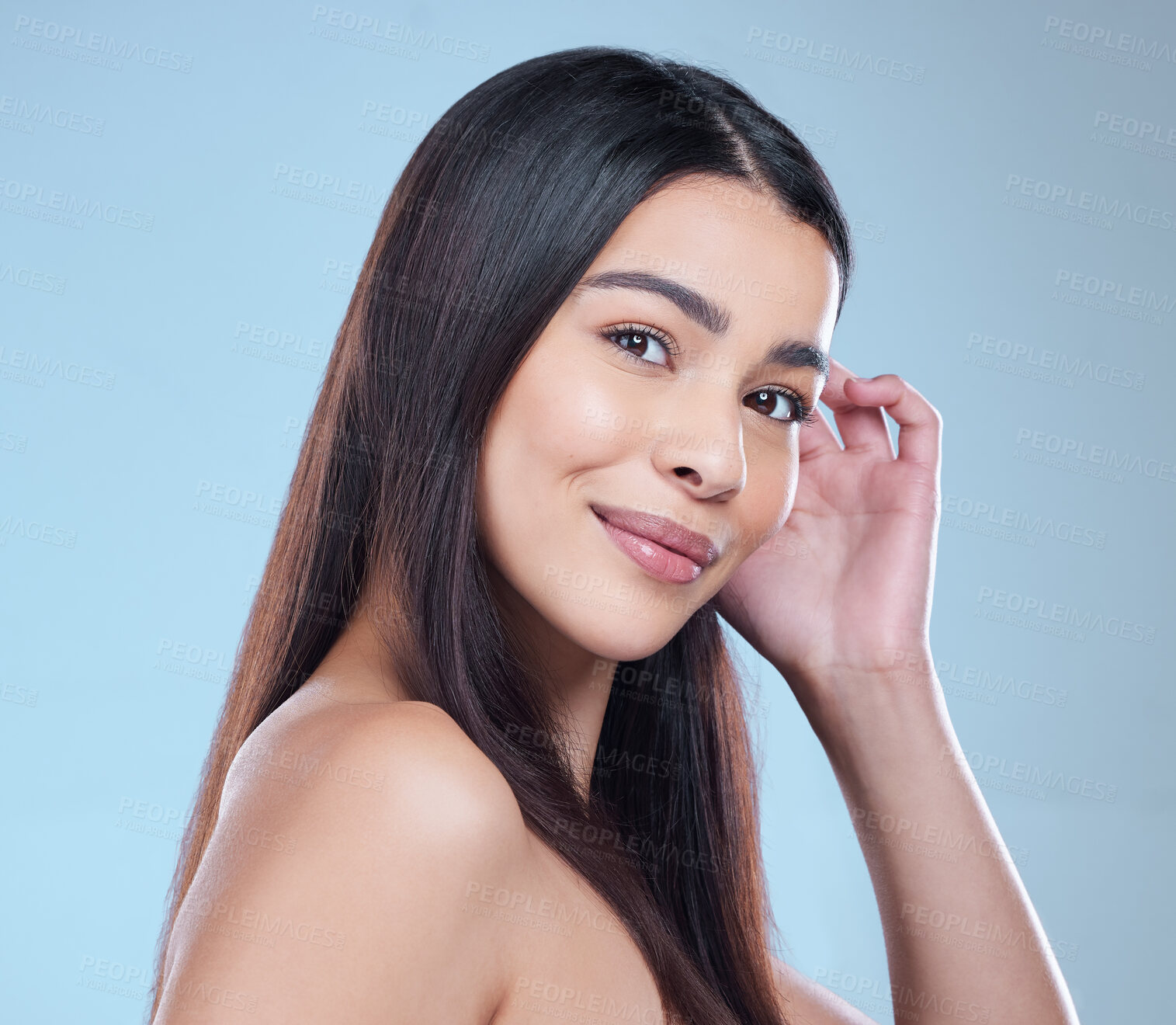 Buy stock photo Studio portrait of a beautiful young woman showing off her long silky hair against a blue background