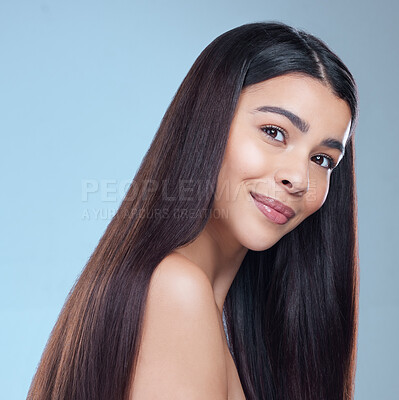 Buy stock photo Studio portrait of a beautiful young woman showing off her long silky hair against a blue background