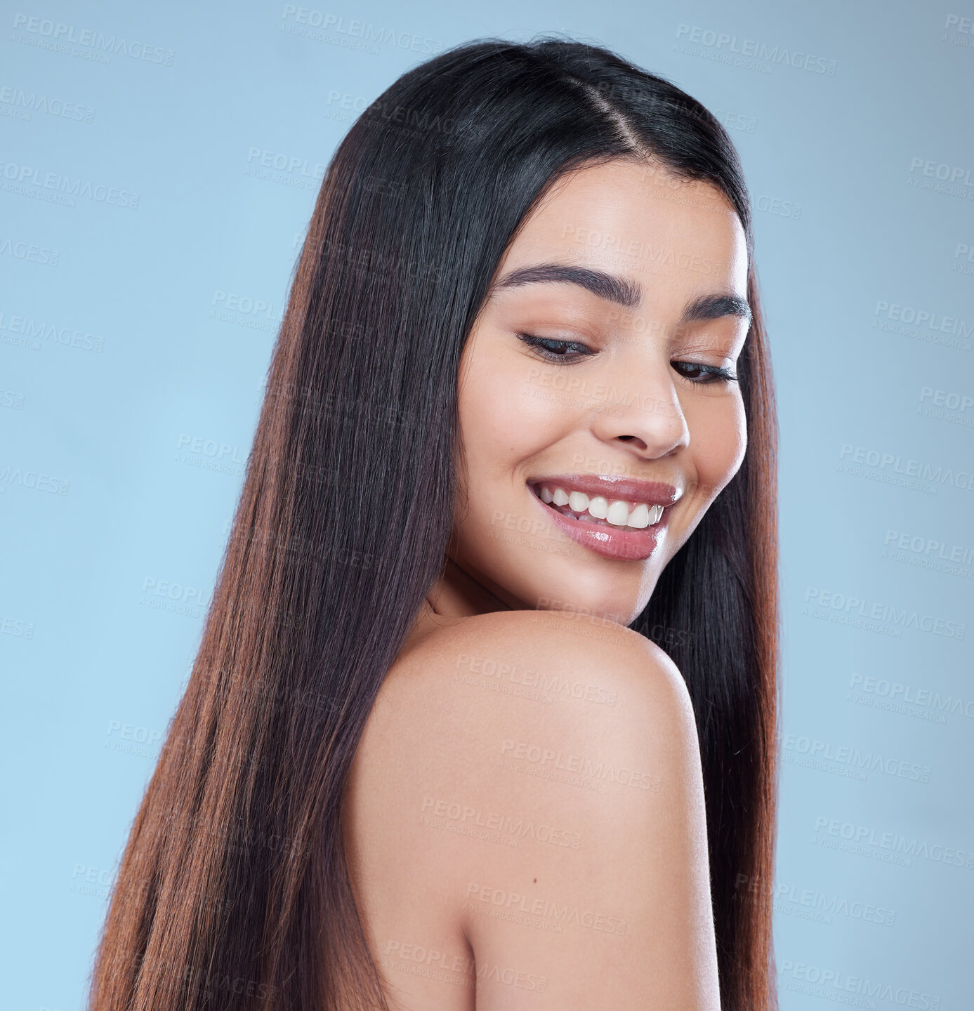 Buy stock photo Studio shot of a beautiful young woman showing off her long silky hair against a blue background