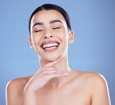 Buy stock photo Shot of an attractive young woman posing alone against a blue background in the studio and laughing