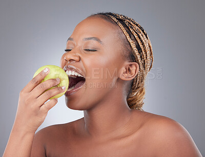 Buy stock photo Black woman, apple and eating for health in studio with diet, nutrition or detox for skincare by white background. Model, person or girl with fruit for vitamin, benefits and hungry with organic food