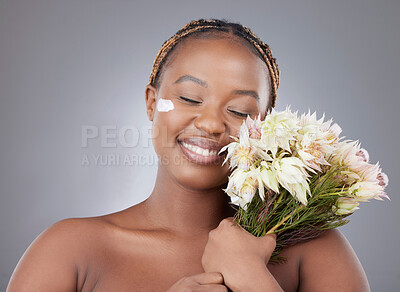 Buy stock photo Woman, face or cream with flowers in studio for natural beauty, organic skincare or eco friendly sunscreen. Model, black person or happy with moisturizer treatment for glowing skin on gray background