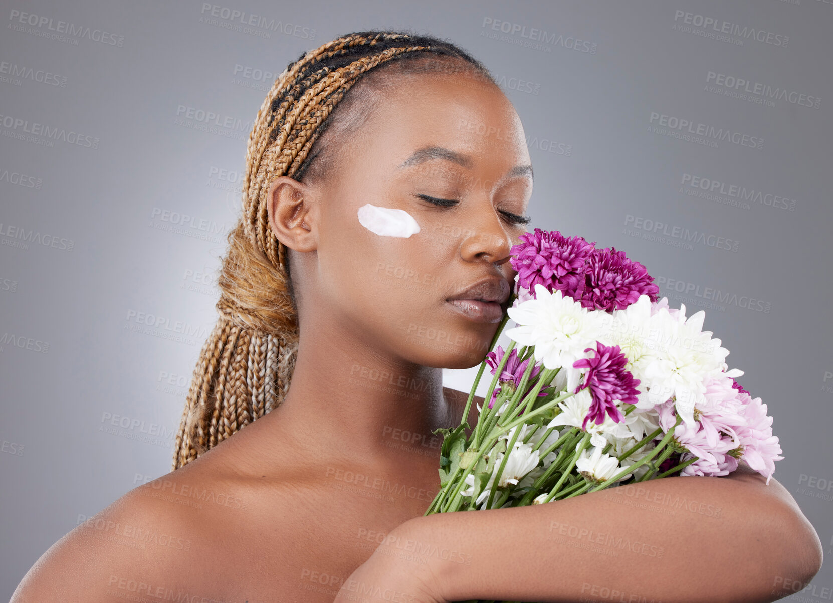 Buy stock photo Woman, face or lotion with flowers in studio for natural beauty, organic skincare or eco friendly sunscreen. Model, black person or serious with moisturizer treatment for skin glow on gray background