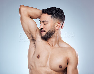 Buy stock photo Smile, man and smelling armpit for hygiene with skin health and deodorant fragrance for self care in studio. Happy male person, underarm and check sweat for clean body and perfume by gray background