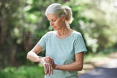 Buy stock photo Senior woman, watch and outdoor for exercise time on run, workout and training on road for fitness. Elderly female person check cardio progress for health and wellness while running in nature