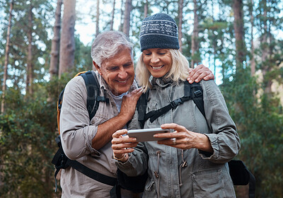 Buy stock photo Phone, hiking and happy senior people in nature with network, social media or video streaming in forest. Mature couple of friends trekking or travel in woods with funny meme, smartphone or mobile app