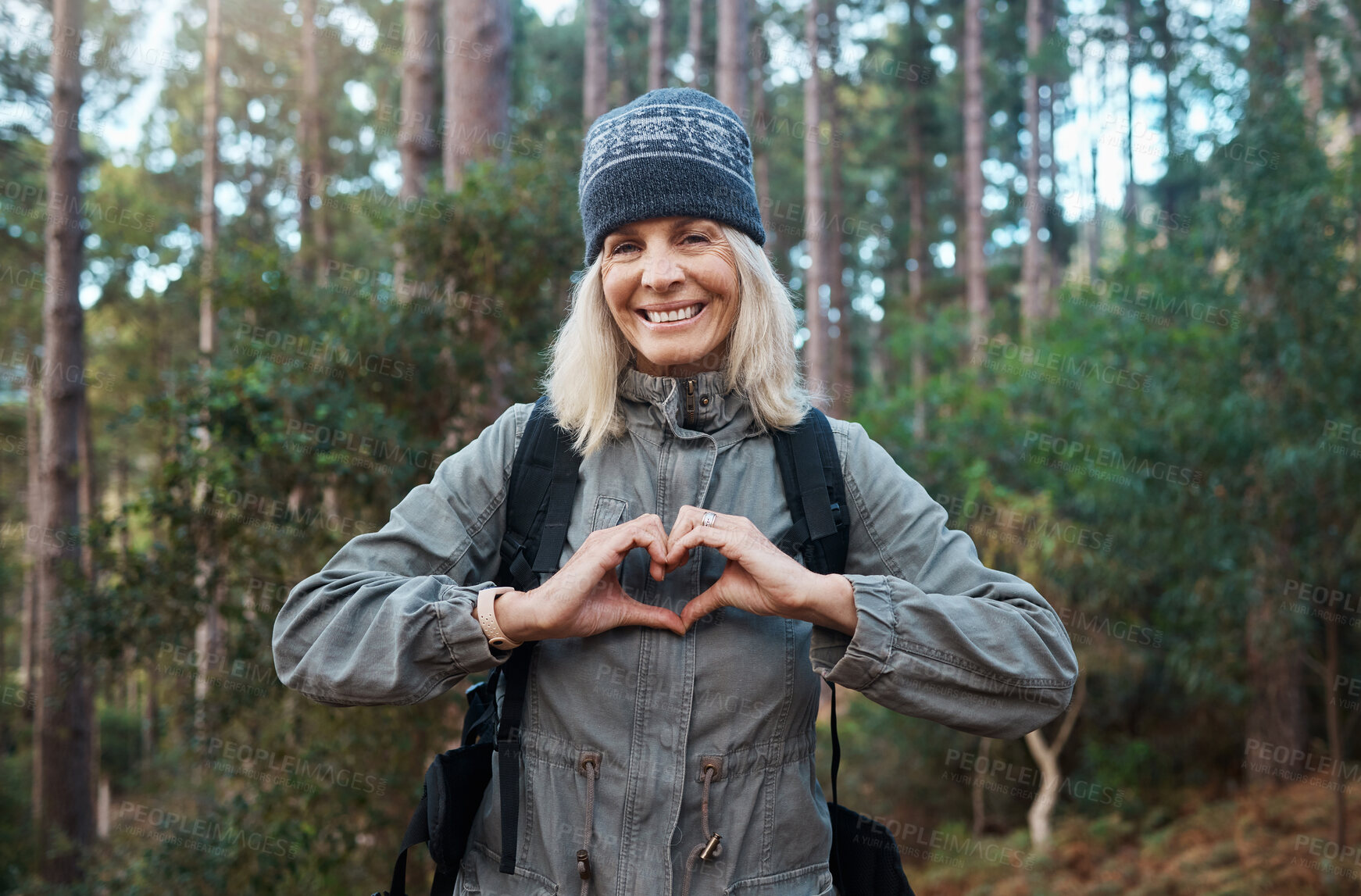 Buy stock photo Portrait, heart and happy woman in forest hiking, fitness and health support, self care hands and cardiovascular workout. Nature, travel or trekking of mature person in woods with love sign or emoji