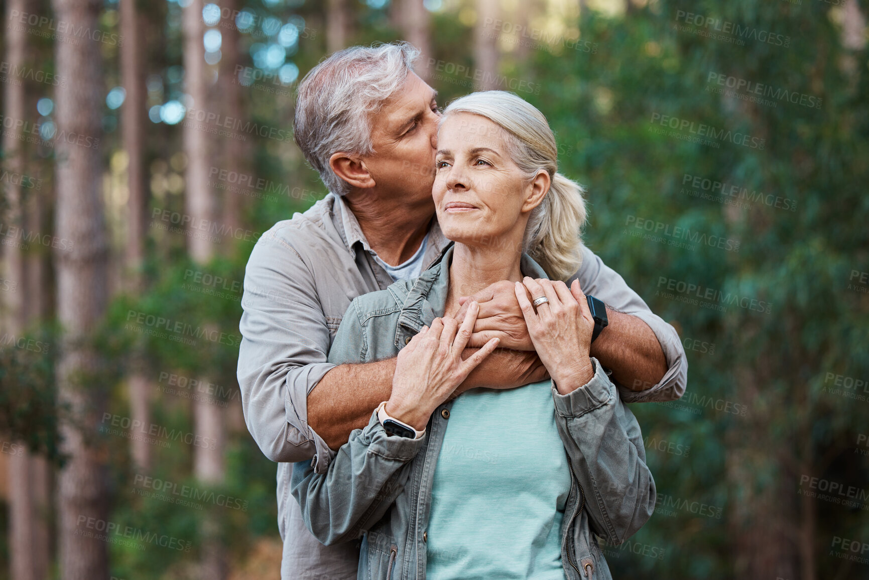 Buy stock photo Hiking, kiss and senior couple with love in a forest, relax and hug while standing in nature park together. Caring, embrace and sweet, elderly man with woman on retirement vacation in the woods