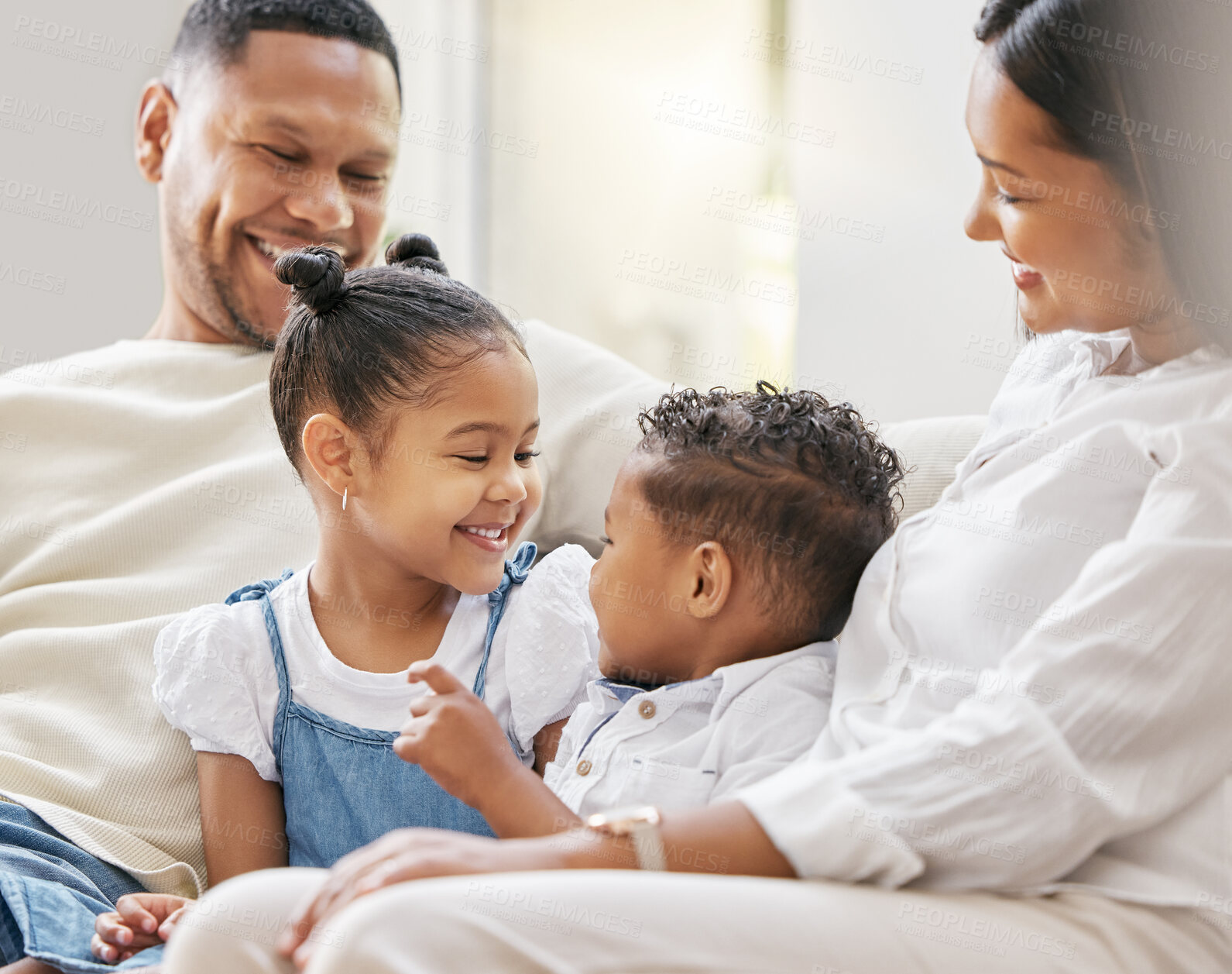 Buy stock photo Shot of a young family happily bonding together on the sofa at home