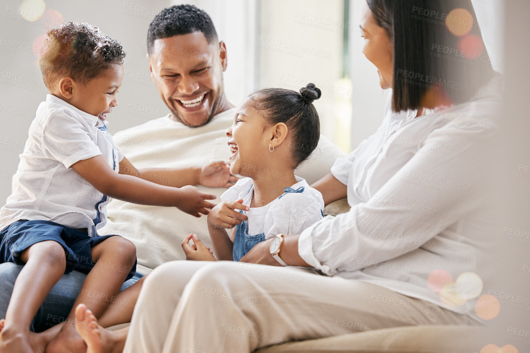 Buy stock photo Shot of a young family happily bonding together on the sofa at home