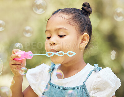 Buy stock photo shot of a little girl blowing bubbles in a garden at home