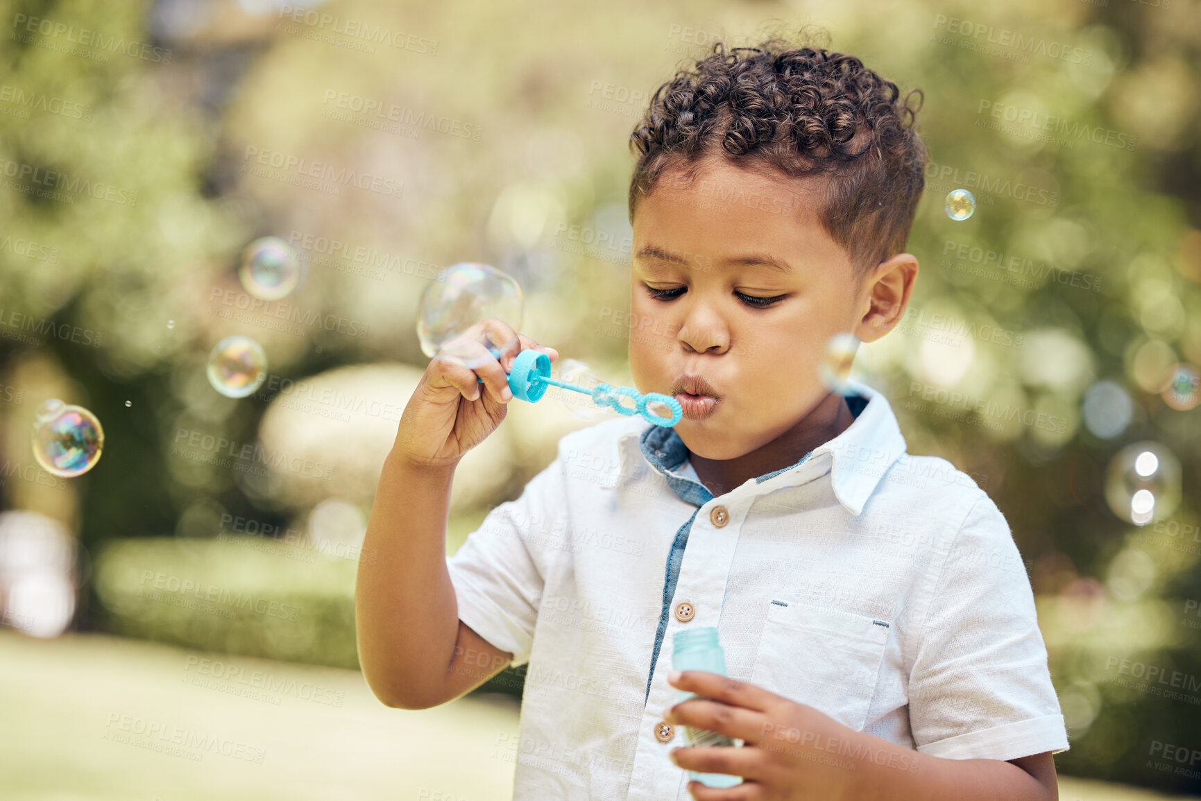 Buy stock photo Boy, kid and blowing bubbles in outdoor park for playing, development or activity. Summer, freedom and young child with soap toy for entertainment, having fun or enjoyment on weekend in backyard