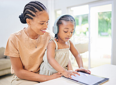 Buy stock photo Shot of an attractive young mother sitting with her daughter and helping her learn on a digital tablet