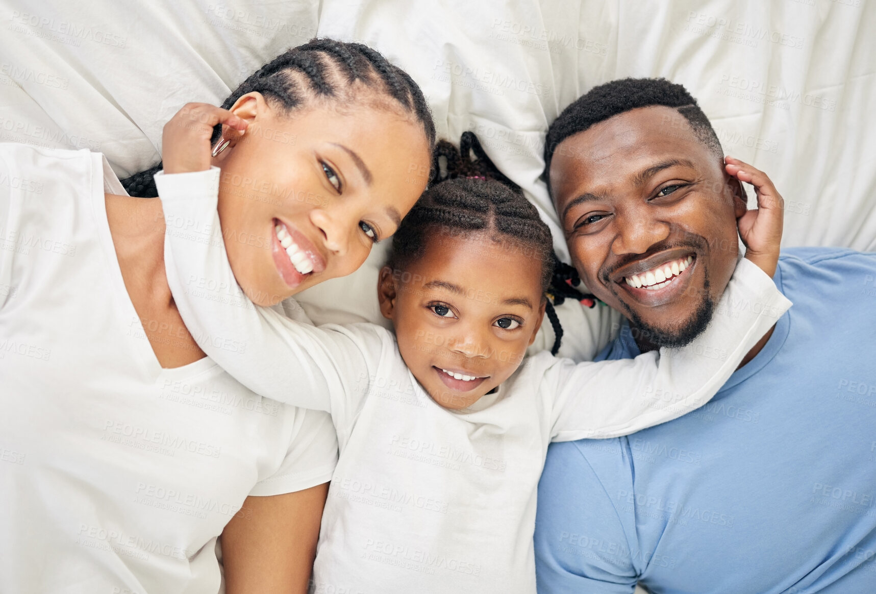 Buy stock photo High angle shot of an adorable little girl lying down and bonding with her parents at home