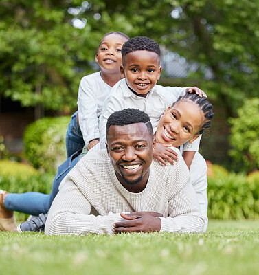 Buy stock photo Portrait, children and a black family lying on the grass in a pile outdoor during summer together for bonding. Mother, father and kids on a field to relax while feeling happy and enjoying love