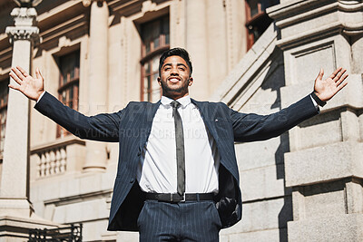 Buy stock photo Cropped shot of a handsome young businessman standing with his arms outstretched in the city