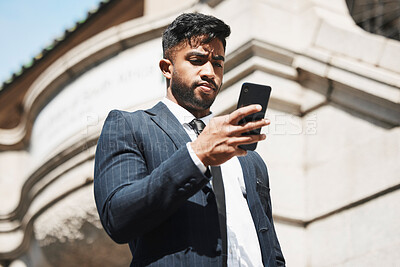 Buy stock photo Cropped shot of a handsome young businessman sending a text message while out in the city