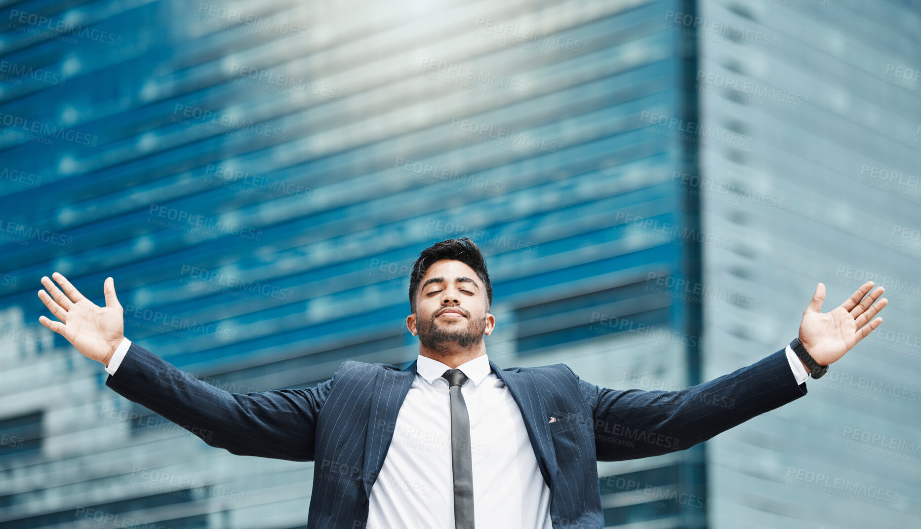 Buy stock photo Cropped shot of a handsome young businessman standing with his arms outstretched in the city