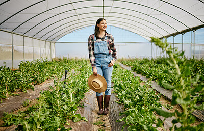 Buy stock photo Shot of a young female farmer standing in her greenhouse