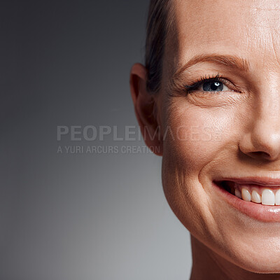 Buy stock photo Portrait, skincare and smile of mature woman in studio on gray background for facial cosmetics. Beauty, half face and space with confident person on mockup for antiaging dermatology treatment