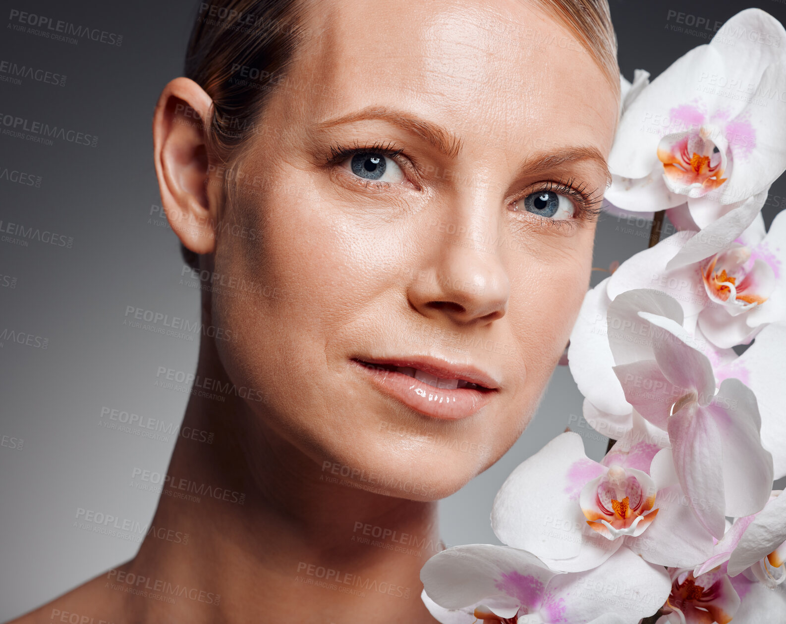 Buy stock photo Beautiful mature woman posing with flowers in studio against a grey background