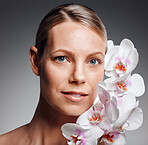 Beautiful mature woman posing with flowers in studio against a grey background