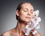 Beautiful mature woman posing with flowers in studio against a grey background