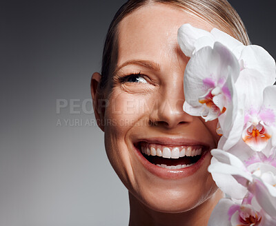 Buy stock photo Beautiful mature woman posing with flowers in studio against a grey background