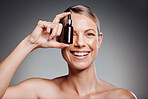 Beautiful mature woman posing with beauty treatment in studio against a grey background