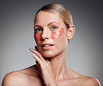 Beautiful mature woman posing with under eye patch in studio against a grey background