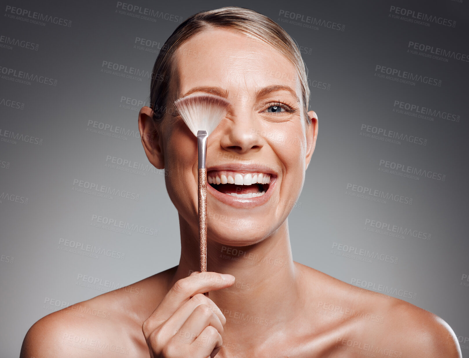 Buy stock photo Portrait, makeup brush and woman with cosmetics, smile and dermatology on gray studio background. Face cover, person and model with equipment, promotion and grooming routine with shine, joy and glow