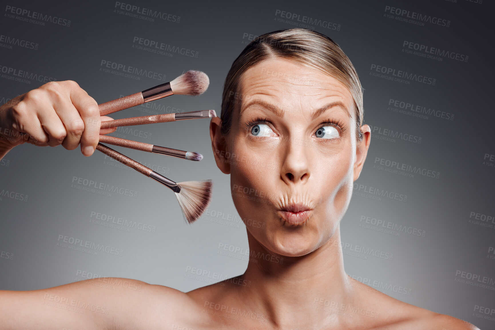 Buy stock photo Funny face, brush or skincare of mature woman in studio for glow, results or transformation on gray background. Facial, joke and playful model with beauty cosmetics for confidence or makeup tools