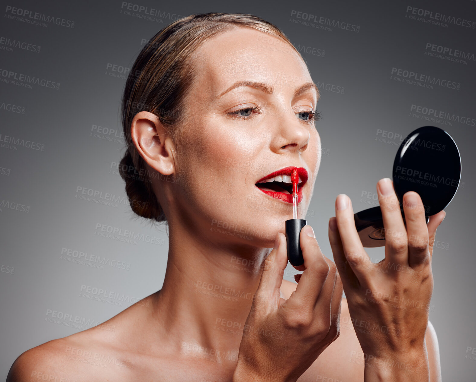 Buy stock photo Woman, mirror and apply lipstick in studio, red color and beauty cosmetics on gray background. Female person, skincare and tool for makeup treatment or product, dermatology and compact for grooming