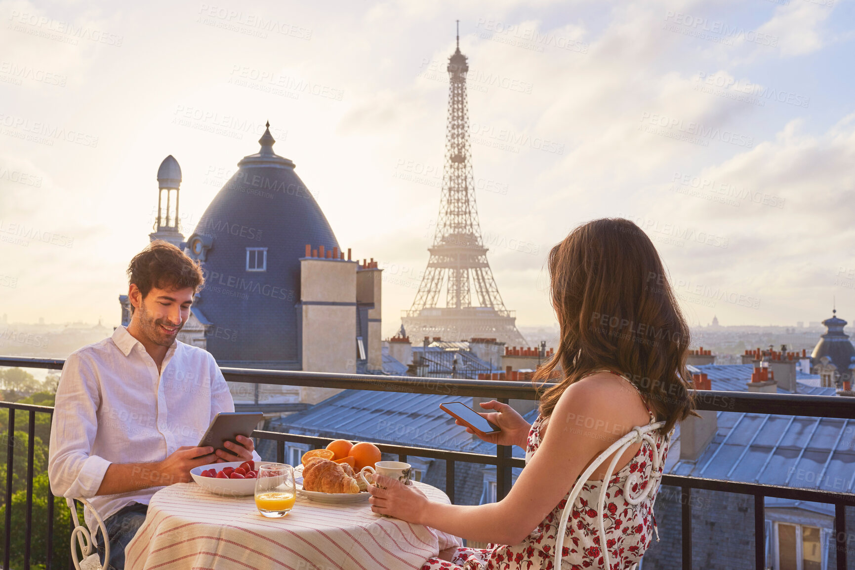 Buy stock photo Travel, breakfast and couple in Paris with the Eiffel Tower on a terrace for romance or anniversary. City, vacation or tourism tech app with a man and woman eating food while looking at a view