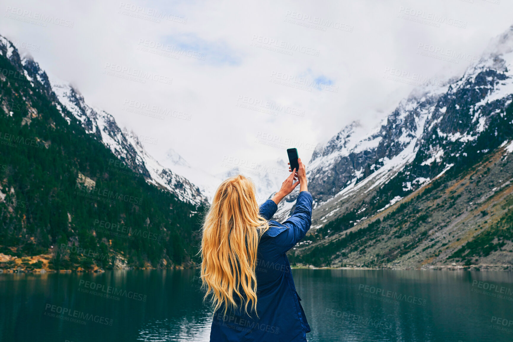 Buy stock photo Mountain, photography and back of person, smartphone and tourist on hike, lake or picture of adventure. Travel, influencer and mobile for memory, river and view of water, holiday or scenery of Canada