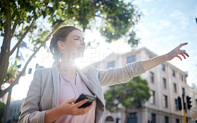 Businesswoman haling a taxi and holding her phone while out in the city