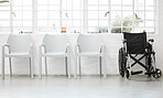 Wheelchair at the end of a row of white chairs in a waiting room