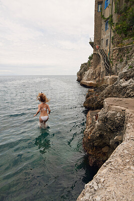 Buy stock photo Shot of an unrecognisable woman jumping into the Mediterranean Sea during her holiday in Italy